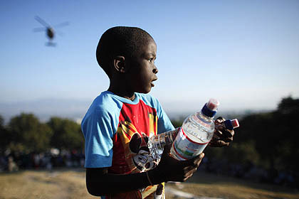 Criança haitiana recebe água de integrante das forças norte-americanas em ponto de distribuição de ajuda em Porto Príncipe 